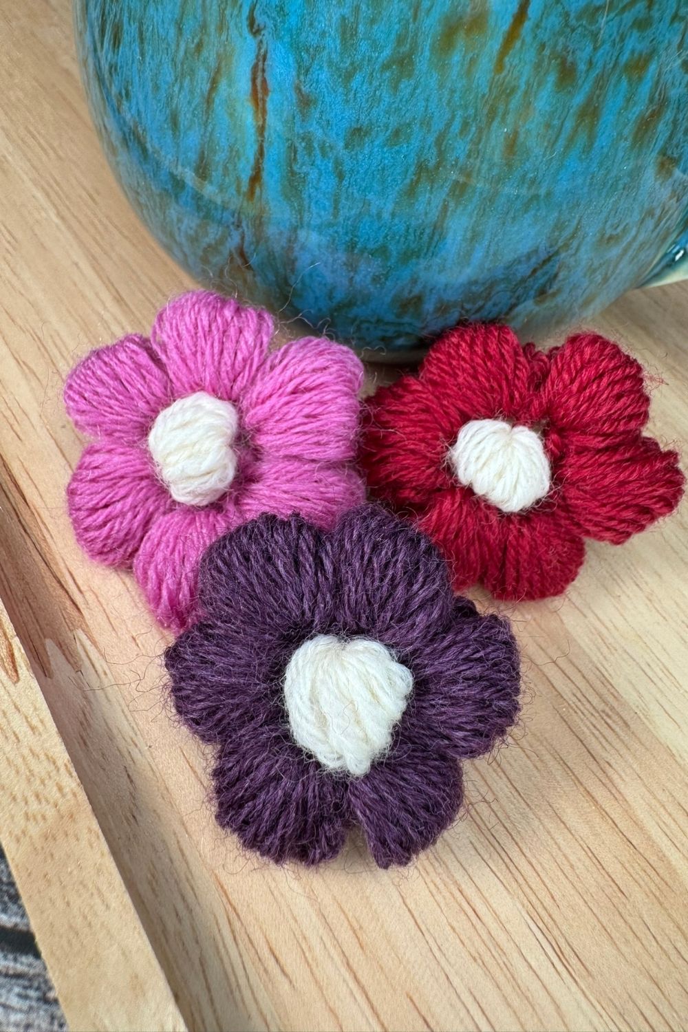 drei gehäkelte Blüten in verschiedenen Farben