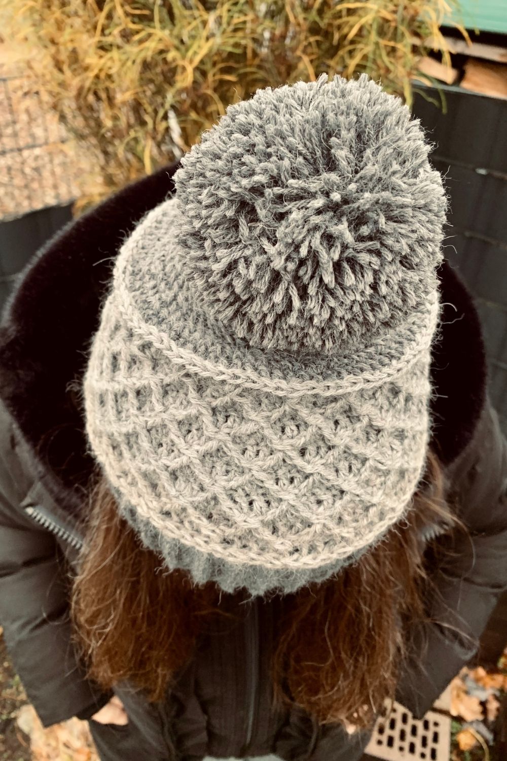 Detailansicht Salino Mütze am Modell in den Farben Hellgrau und Dunkelgrau mit Bommel für kalte Wintertage