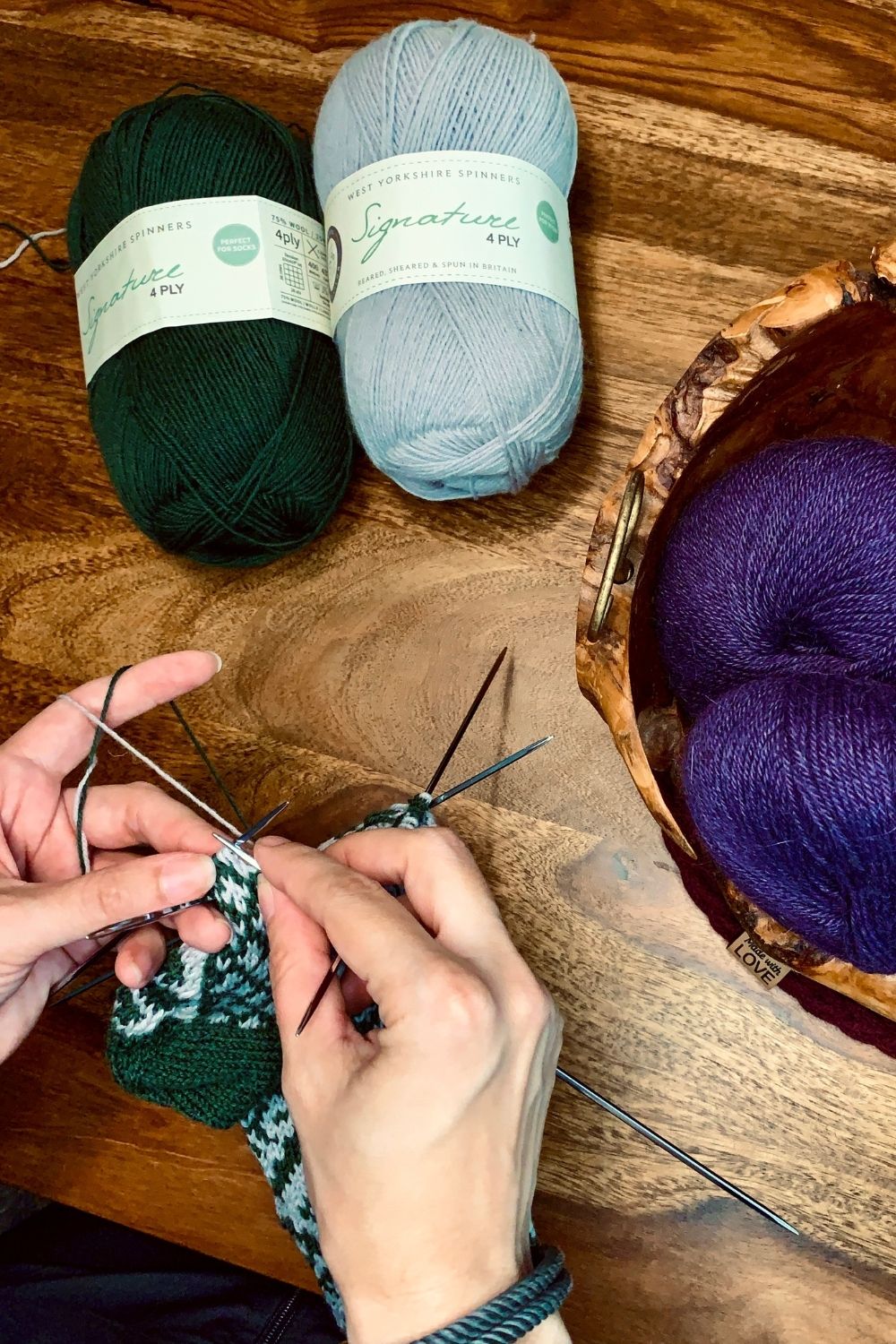 Work in progress, hier entstehen gerade die handgestrickten Saint Patrick Socken, im Hintergrund Wolle auf dem Holztisch
