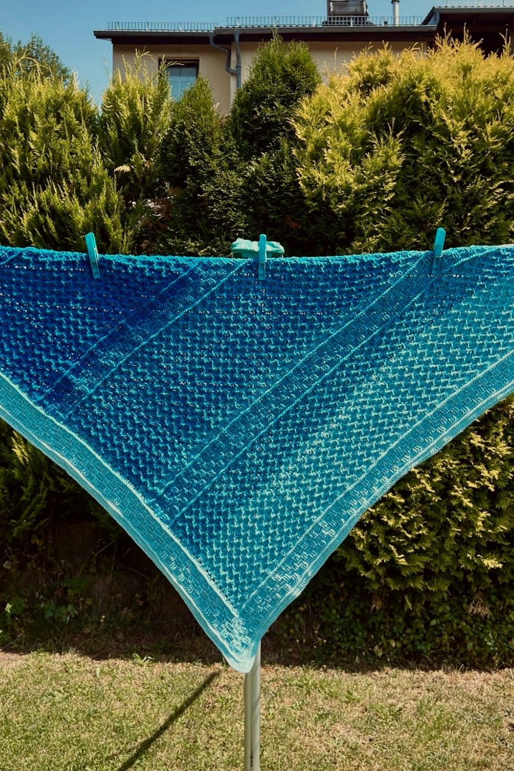Tuch Capo Bianco hängt auf Wäscheleine, mit Fokus auf die verschiedenen Muster, gehäkelt aus blauem Verlaufsgarn