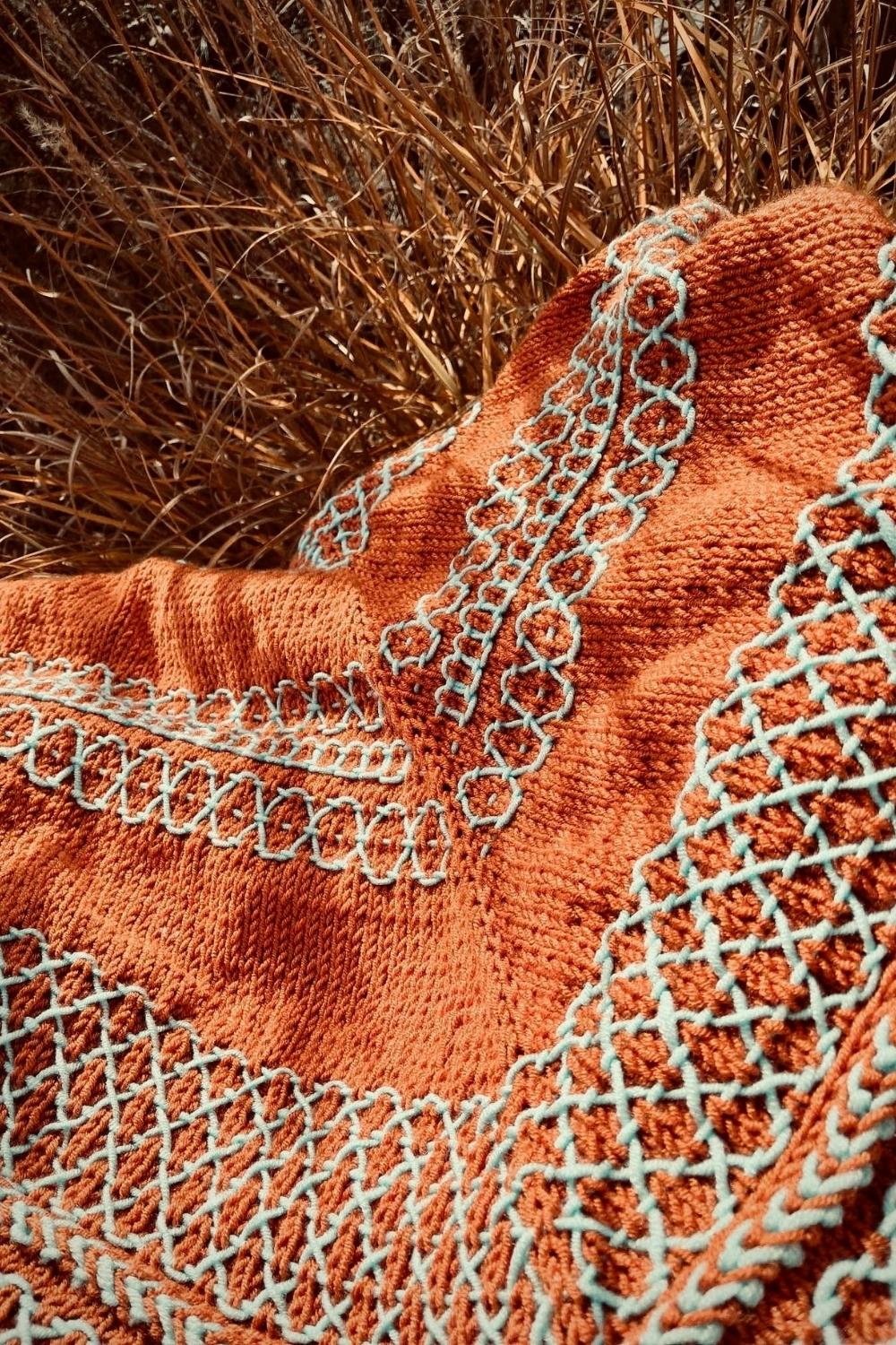 Stricktuch Kodawari in orange mit hellblauem Sashikomuster liegt in Düne mit Fokus auf das Muster
