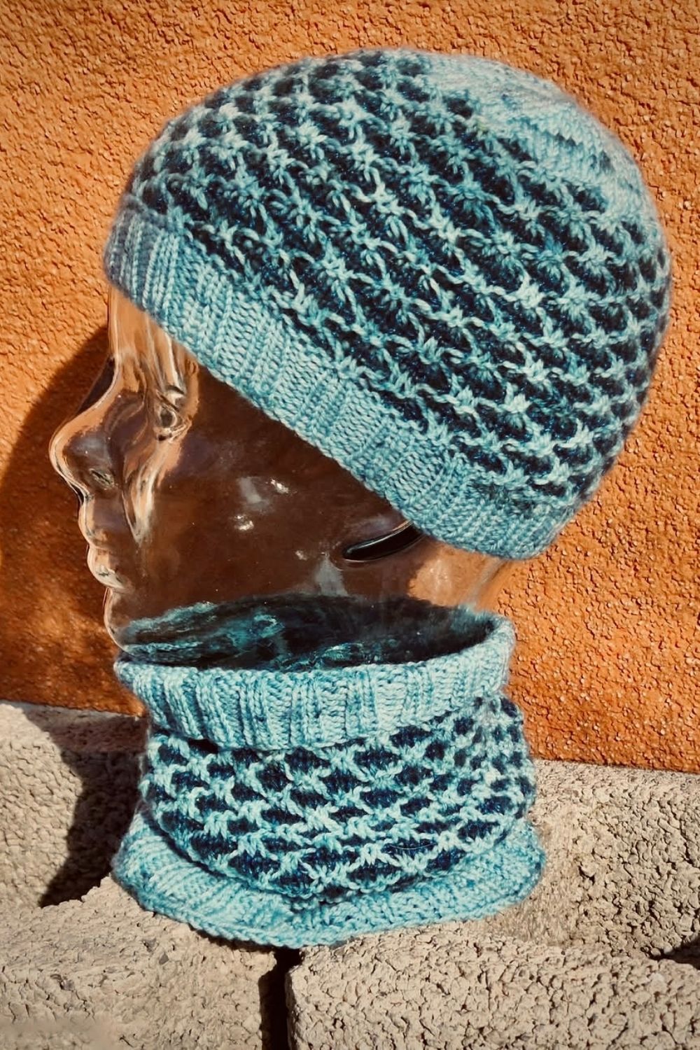 Strickset Dünenwind: Mütze und Cowl in den Farben Türkis und Dunkelblau auf Dekokopf fotografiert