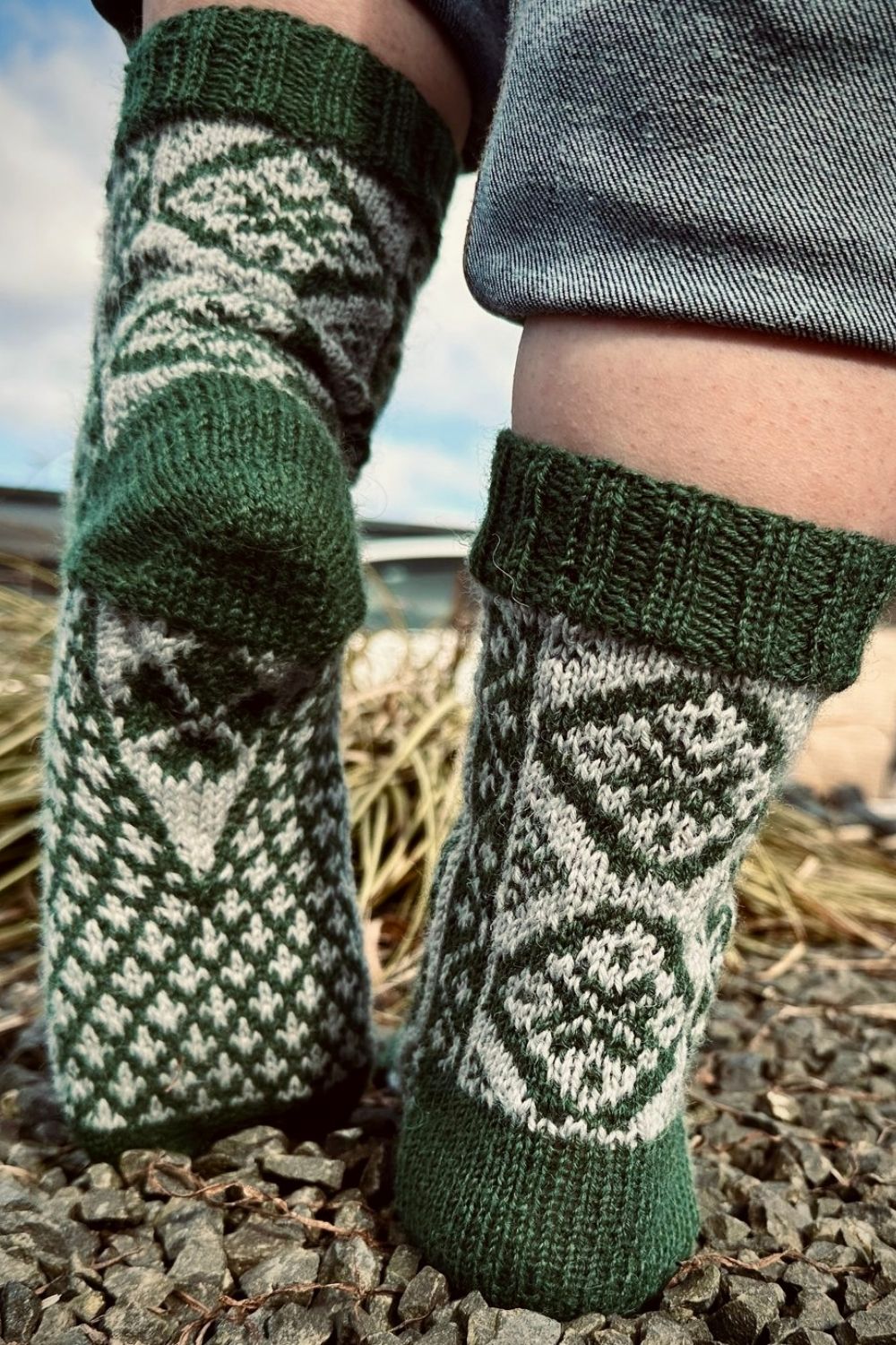 Die handgestrickten Saint Patrick Socken gemütlich an den Füßen mit Fokus auf Rückseite und Sohle